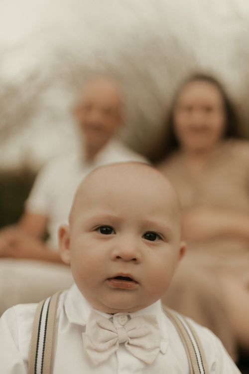 Free A close-up portrait of a baby with blurred parents in the background. Stock Photo