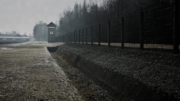 Barbed wire fence and watchtower at Dachau Concentration Camp in Germany.