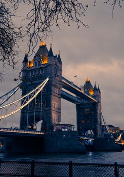 Scenic evening view of the iconic Tower Bridge in London with warm lights reflecting on the River Thames.