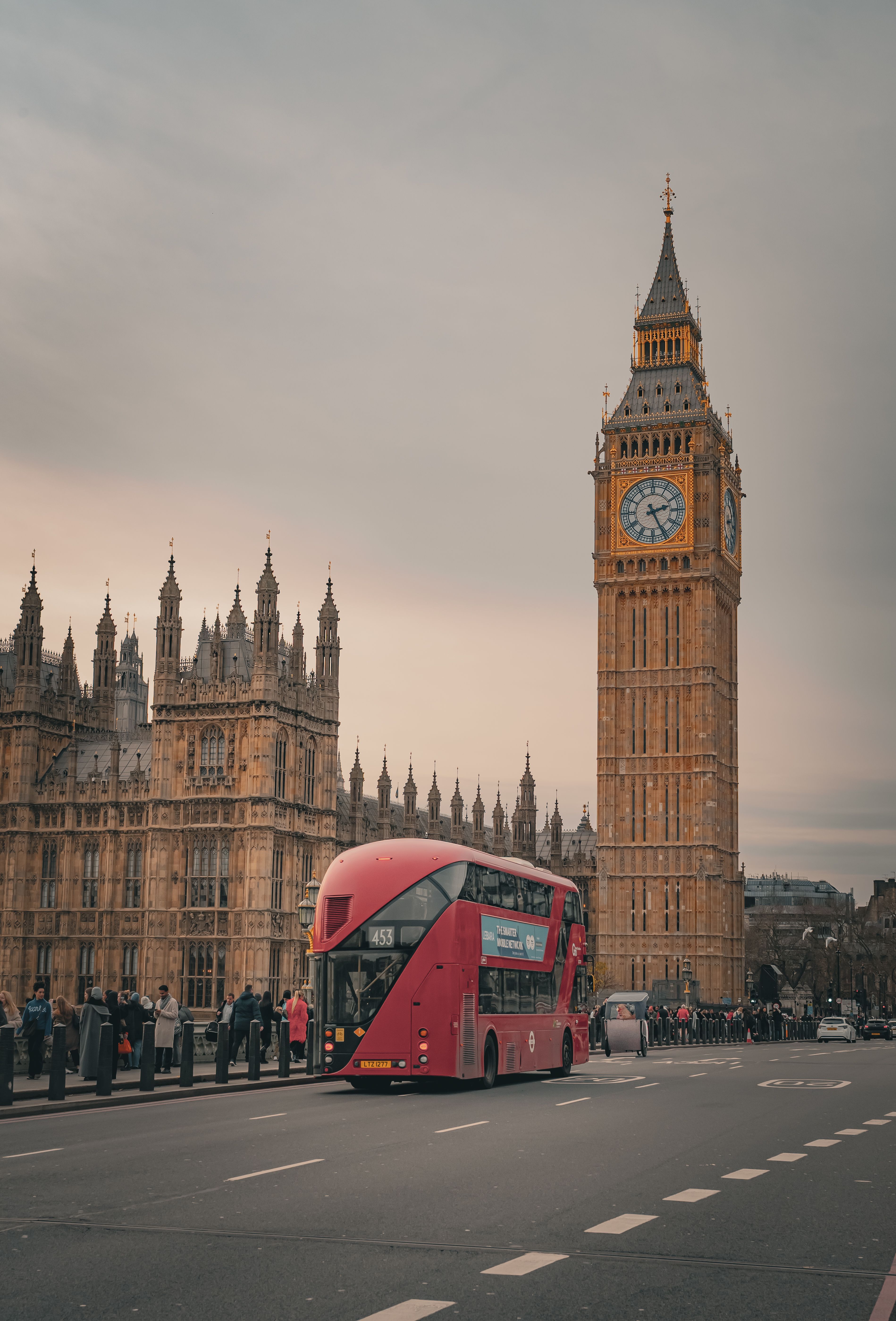 Iconic red double-decker bus passing by Big Ben in London, Vereinigtes Königreich.