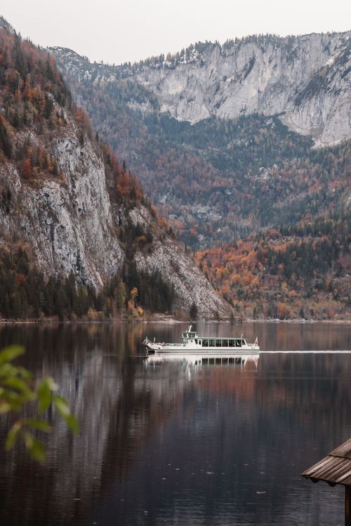Free A peaceful boat glides on a calm lake surrounded by autumn mountains in Austria. Stock Photo