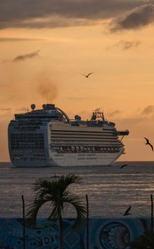 A luxurious cruise ship sails at sunset, creating a picturesque scene with a serene ocean backdrop. Ideal for travel and tourism content.