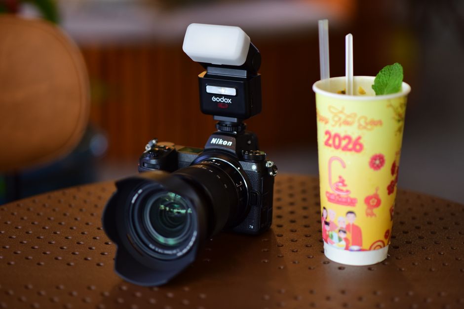 A Nikon camera with flash next to a festive drink cup, perfect for event photography.