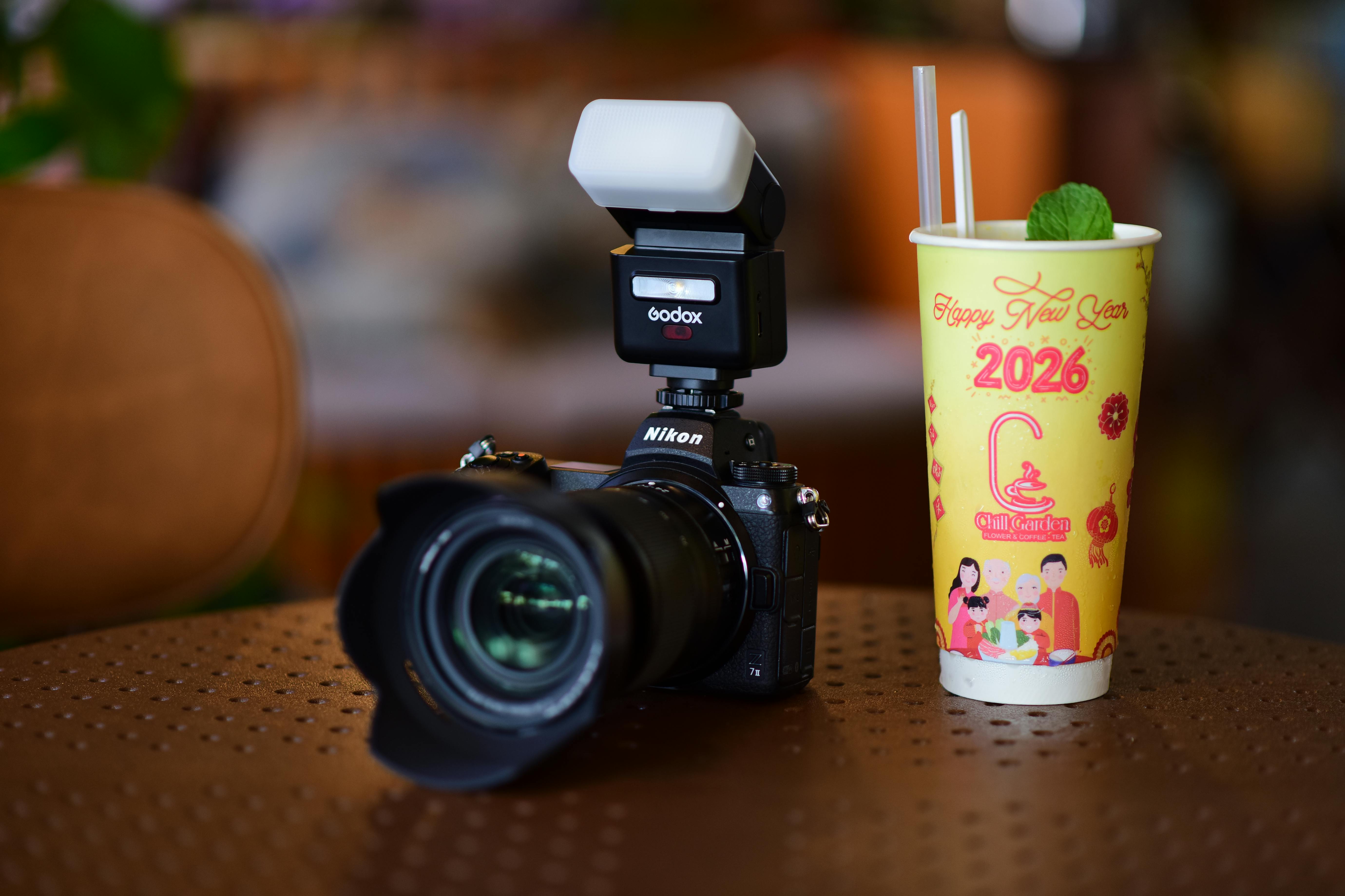 A DSLR camera and a festive drink cup celebrating New Year 2026 on a table.