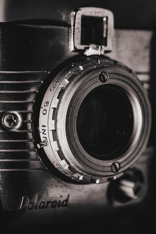 Free Close-up of a vintage Polaroid camera lens in black and white lighting, showcasing intricate details. Stock Photo