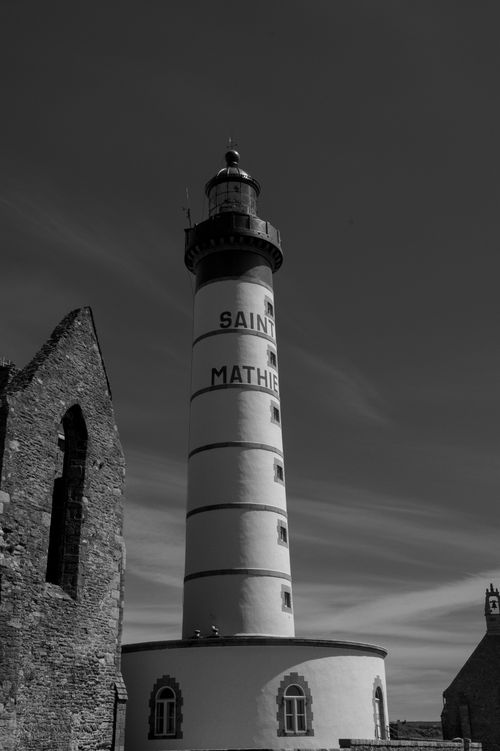 Free Saint-Mathieu Lighthouse in black and white, located in Brittany, France with historic ruins nearby. Stock Photo