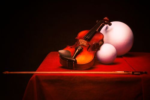 Free Artistic still life of a violin on a red surface with geometric shapes. Stock Photo