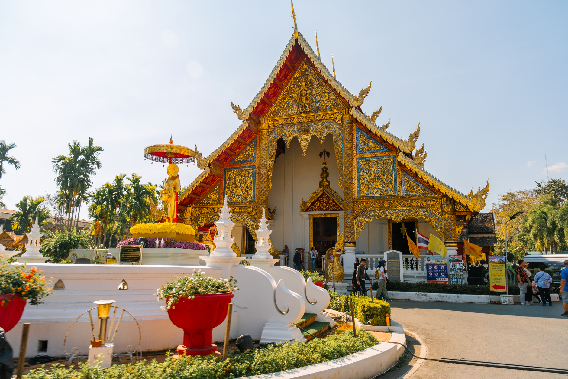 Stunning view of a golden temple in Chiang Mai with intricate details and floral décor.