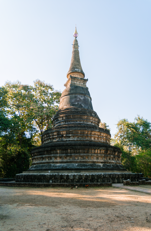 Free Historic stupa in Chiang Mai, Thailand, surrounded by lush greenery under a clear sky. Stock Photo