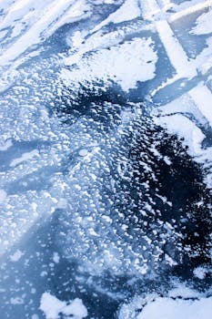 Close-up view of a frozen ice surface with unique snow patterns and textures in a winter setting.