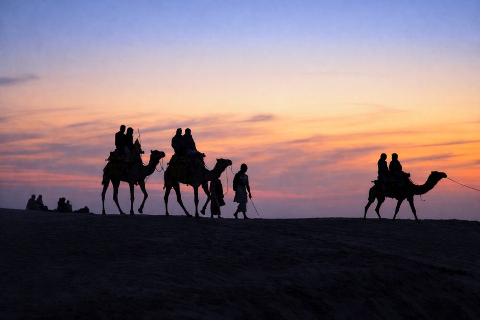 A scenic camel ride at sunset in the deserts of Jaisalmer, Rajasthan, offering a beautiful silhouette.