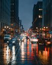 夜晚的城市交通充满活力，建筑灯火通明，潮湿的街道上映出倒影