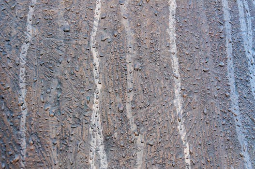 Detailed view of water droplets on a brown textured surface with a vertical pattern.