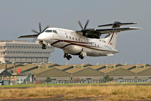 White commercial aircraft landing smoothly on an airport runway with buildings in the background.
