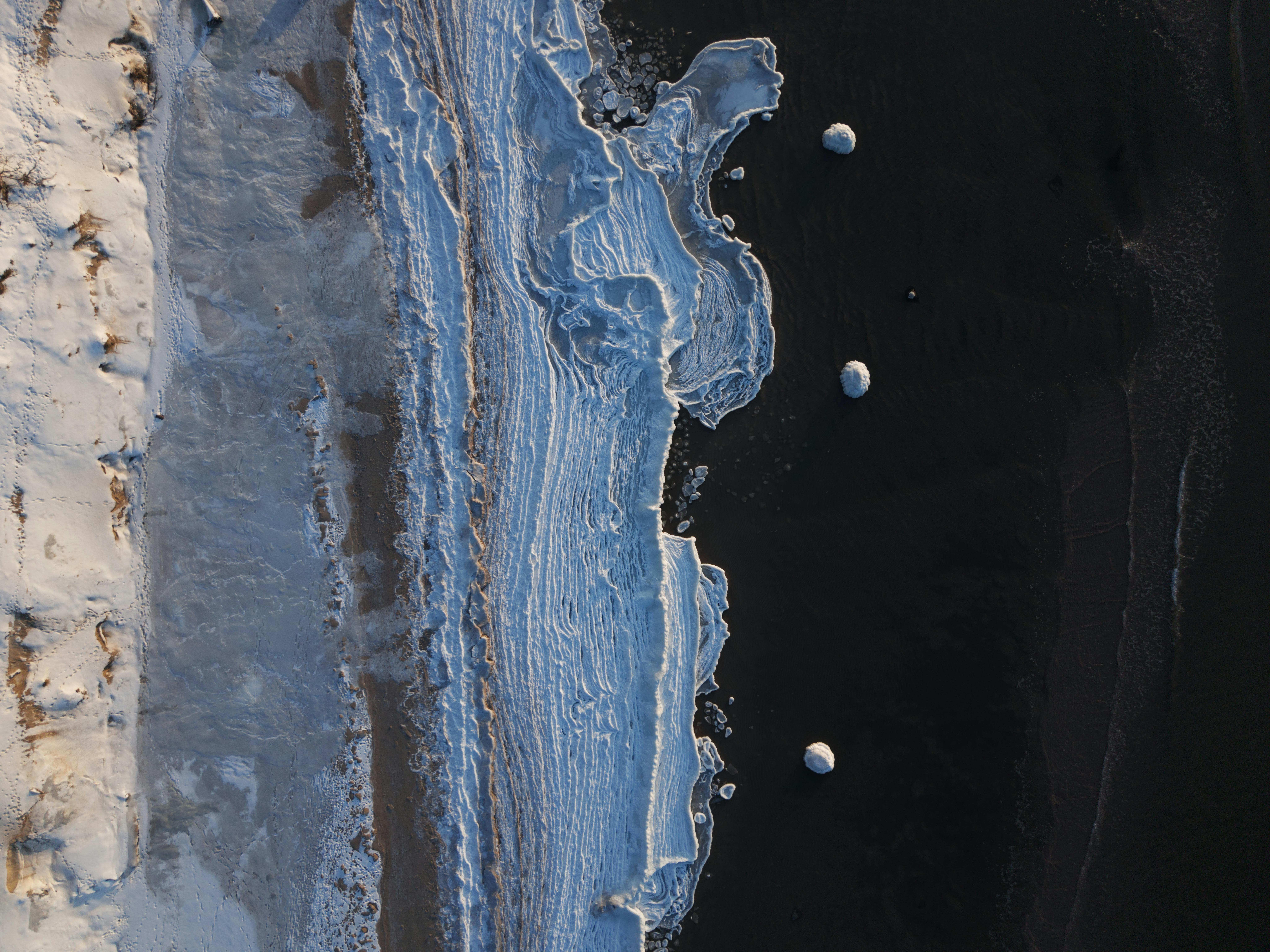 grátis Uma impressionante foto aérea do gelo marinho congelado ao longo de uma praia em Ventspils, Letônia, durante o inverno. Foto profissional