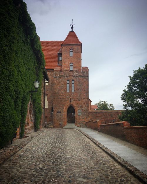 Free Cobblestone path leading to a historic brick castle entrance in Torun, Poland. Stock Photo