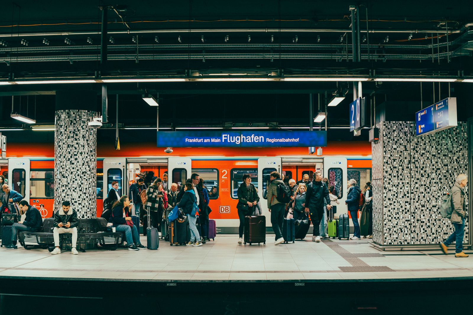 Airport train platform with passengers waiting and luggage nearby