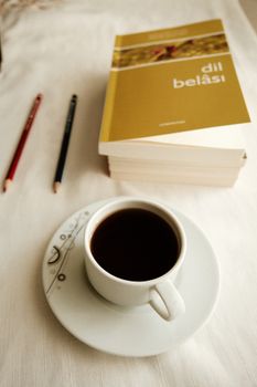 Warm and inviting reading scene with coffee, books, and pencils on a table.
