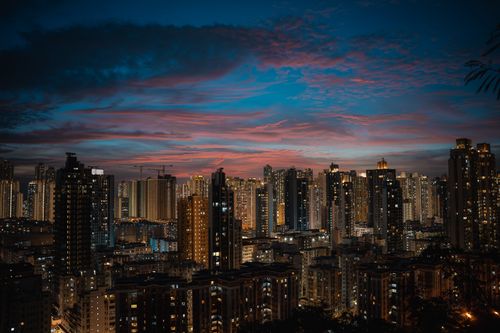 Free Stunning view of Hong Kong's cityscape at twilight, featuring illuminated skyscrapers and dramatic evening clouds. Stock Photo