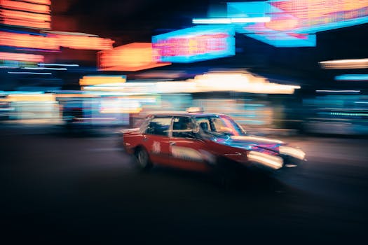 Blurred red taxi speeding through neon-lit streets of Hong Kong at night.