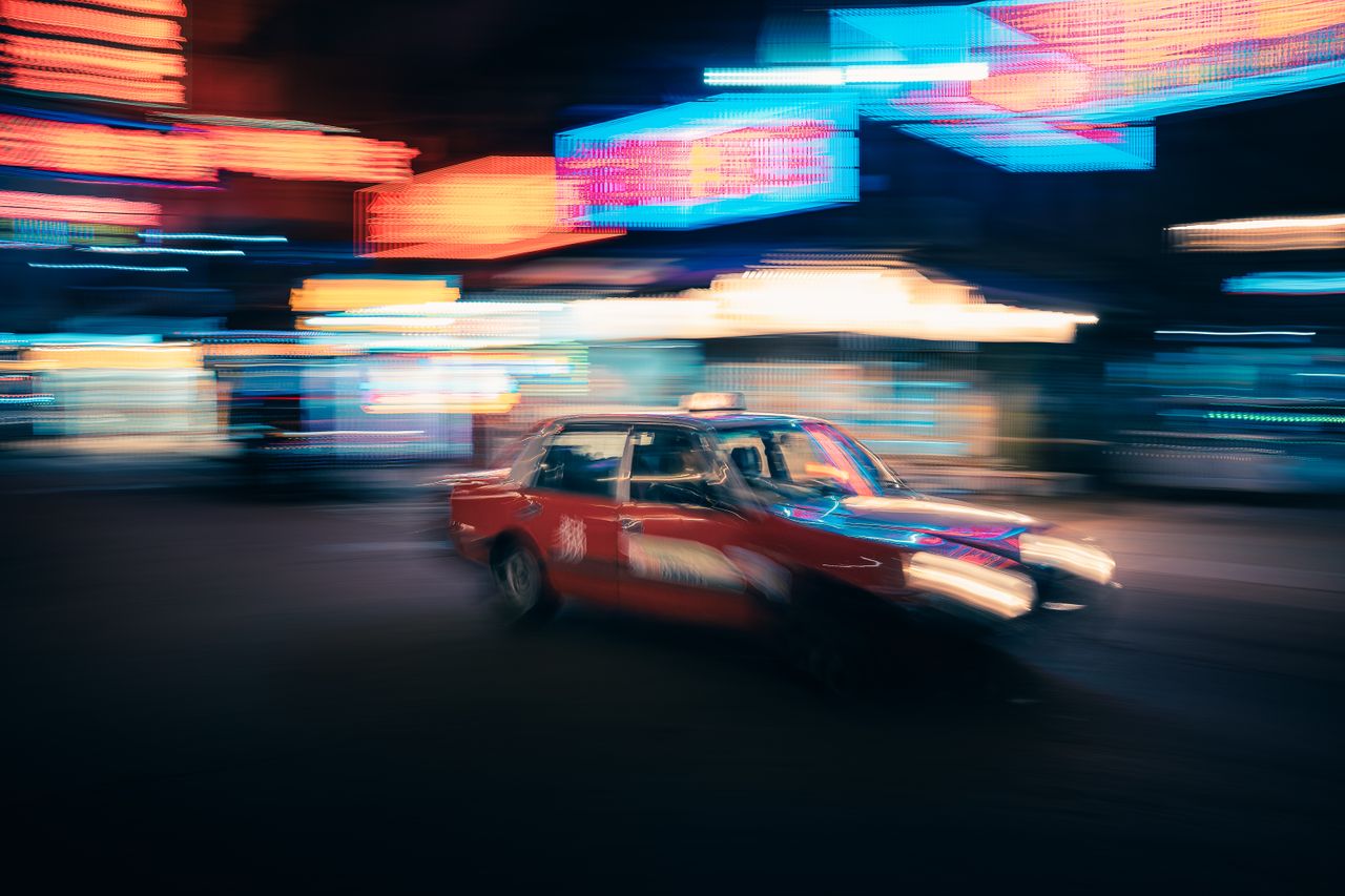 blurred red taxi speeding through neon lit streets of hong kong at nig