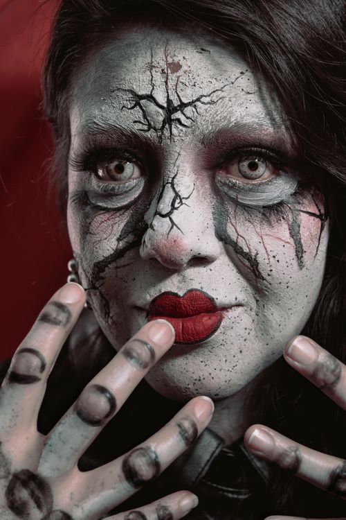 Free Vibrant close-up portrait of a woman with dramatic artistic, cracked-effect makeup and red lipstick. Stock Photo