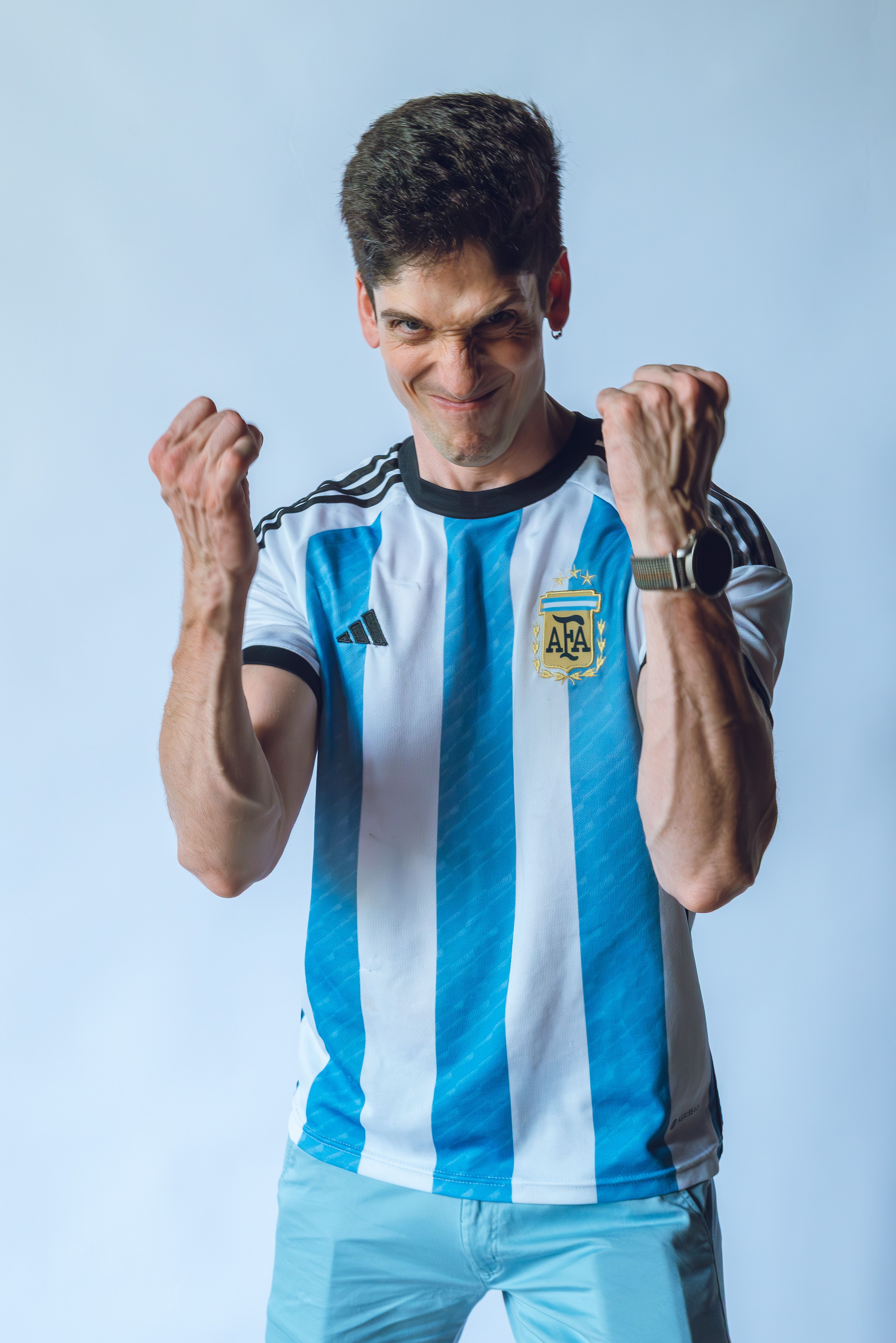 A passionate fan celebrates wearing an Argentina soccer jersey indoors.