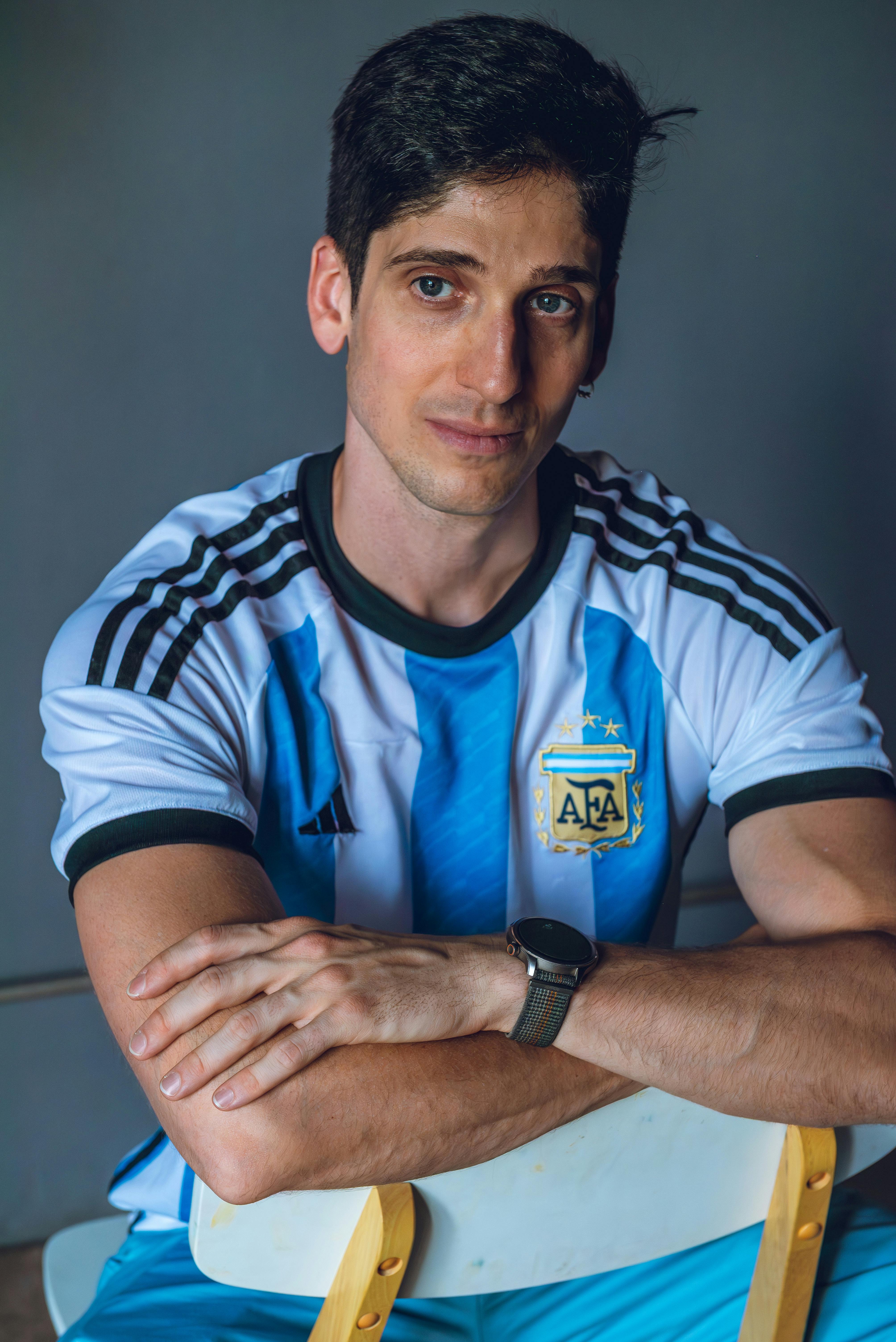 Man in Argentina national soccer team shirt posing indoors.