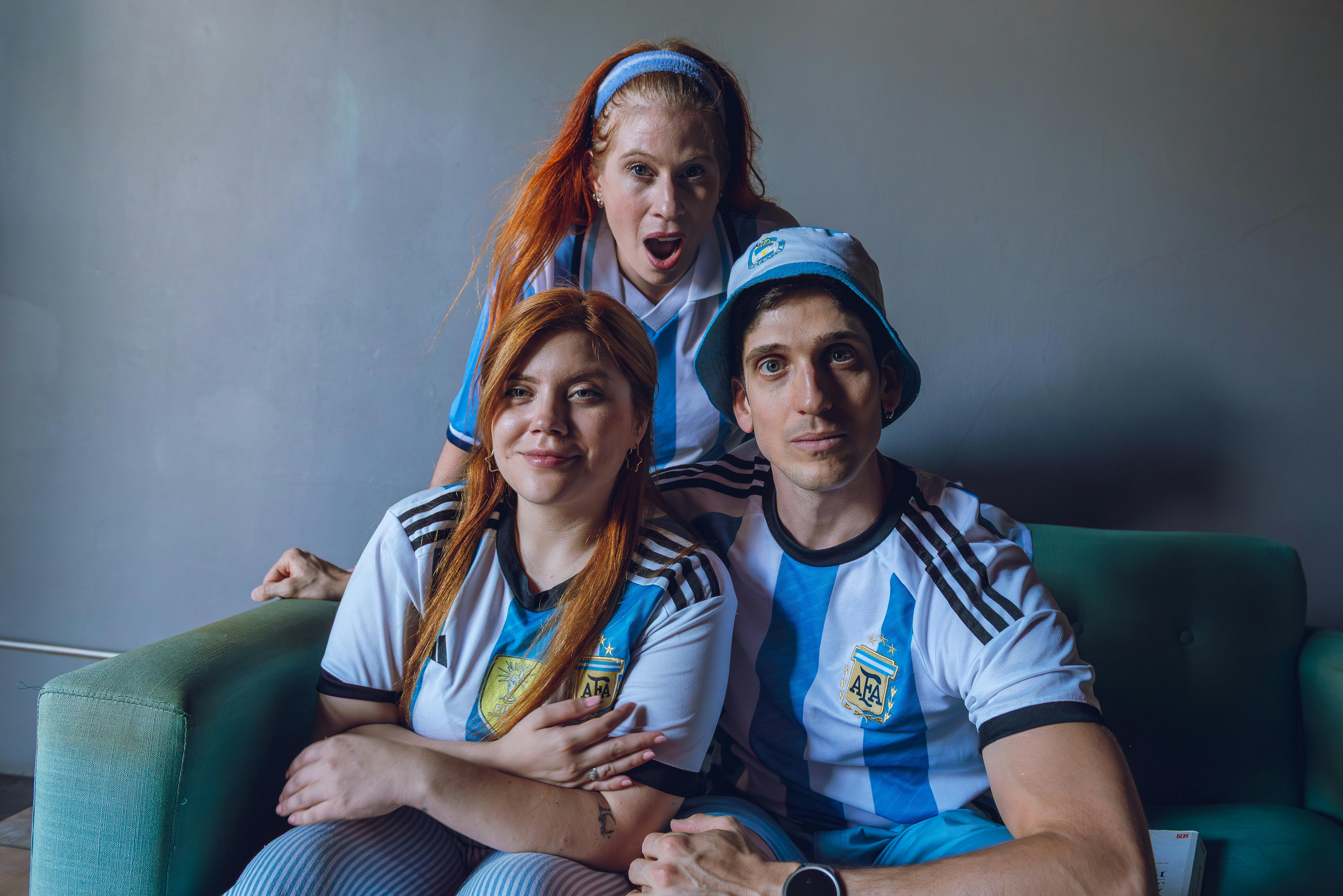 Group of fans in Argentina soccer jerseys expressing excitement indoors.