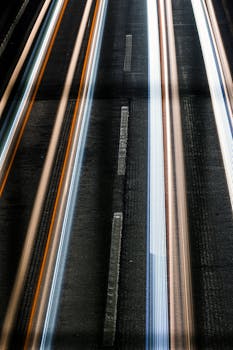 Long exposure capture of colorful light trails on a highway at night, showcasing motion and speed.