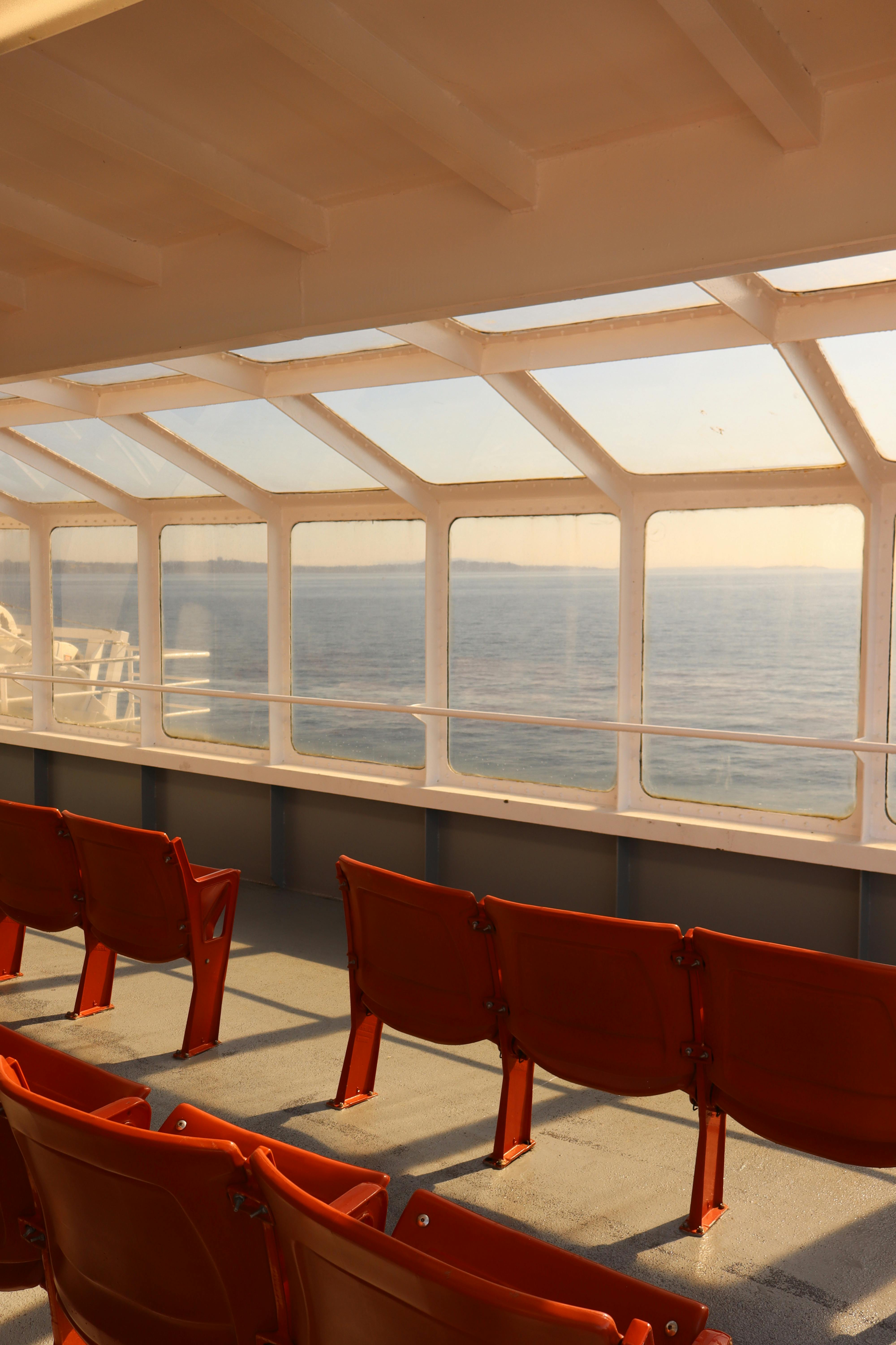 Peaceful empty ferry deck with red seats and ocean view during sunset, offering calmness and tranquility.