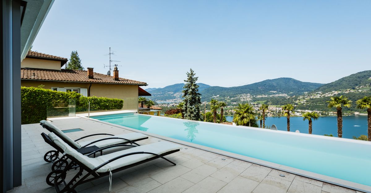 Elegant lakeside infinity pool with stunning mountain and water views, perfect for relaxation and summer leisure.