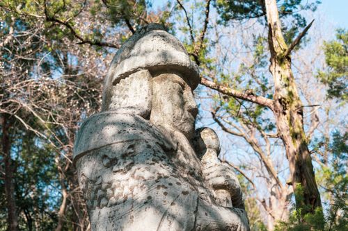 Free A historic stone warrior statue stands amidst a serene forest backdrop. Stock Photo
