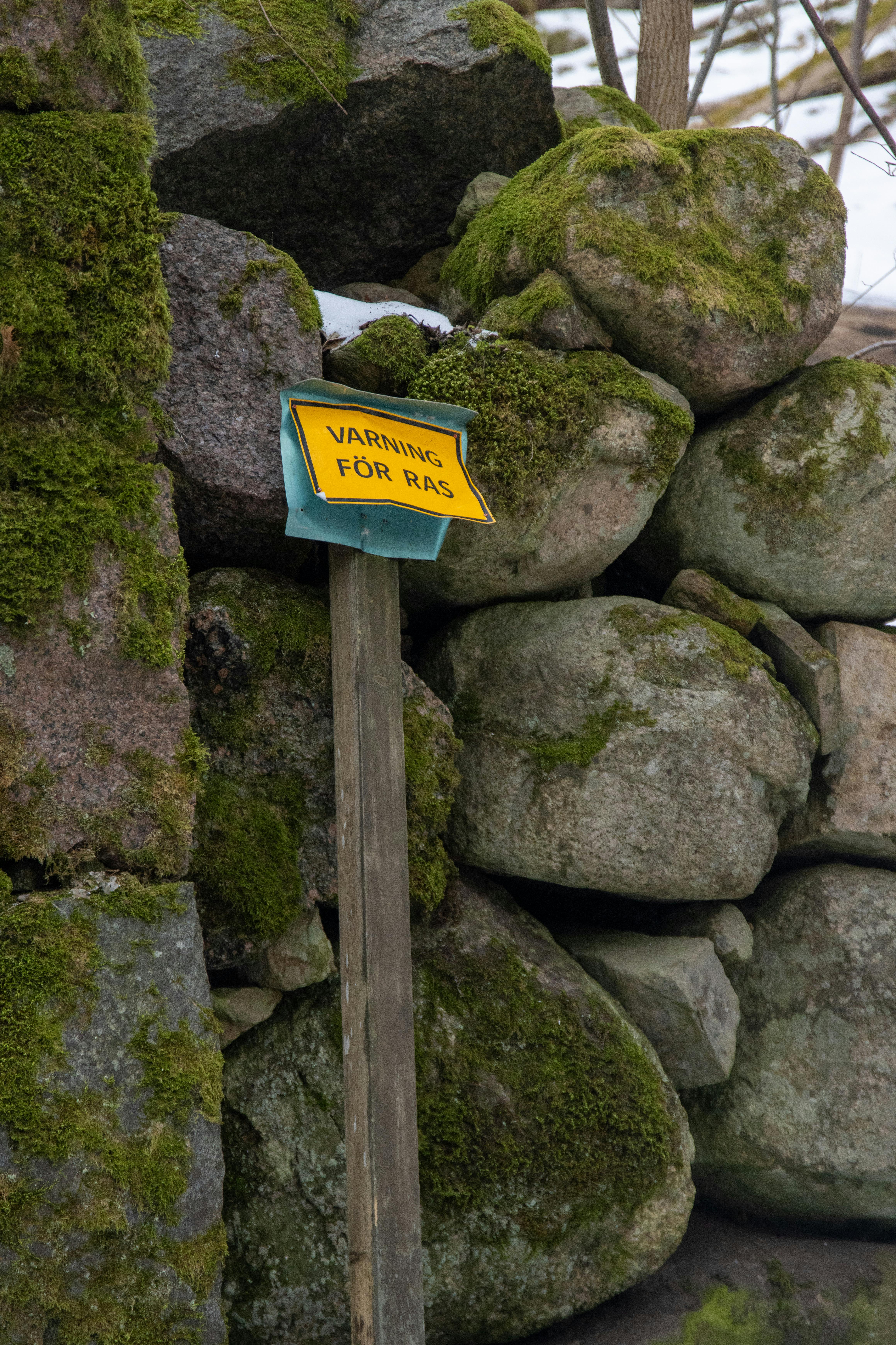 Moss-covered stones with a warning sign in Gränna, Sweden.