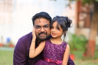 Charming outdoor portrait of a father with his daughter in matching purple outfits.