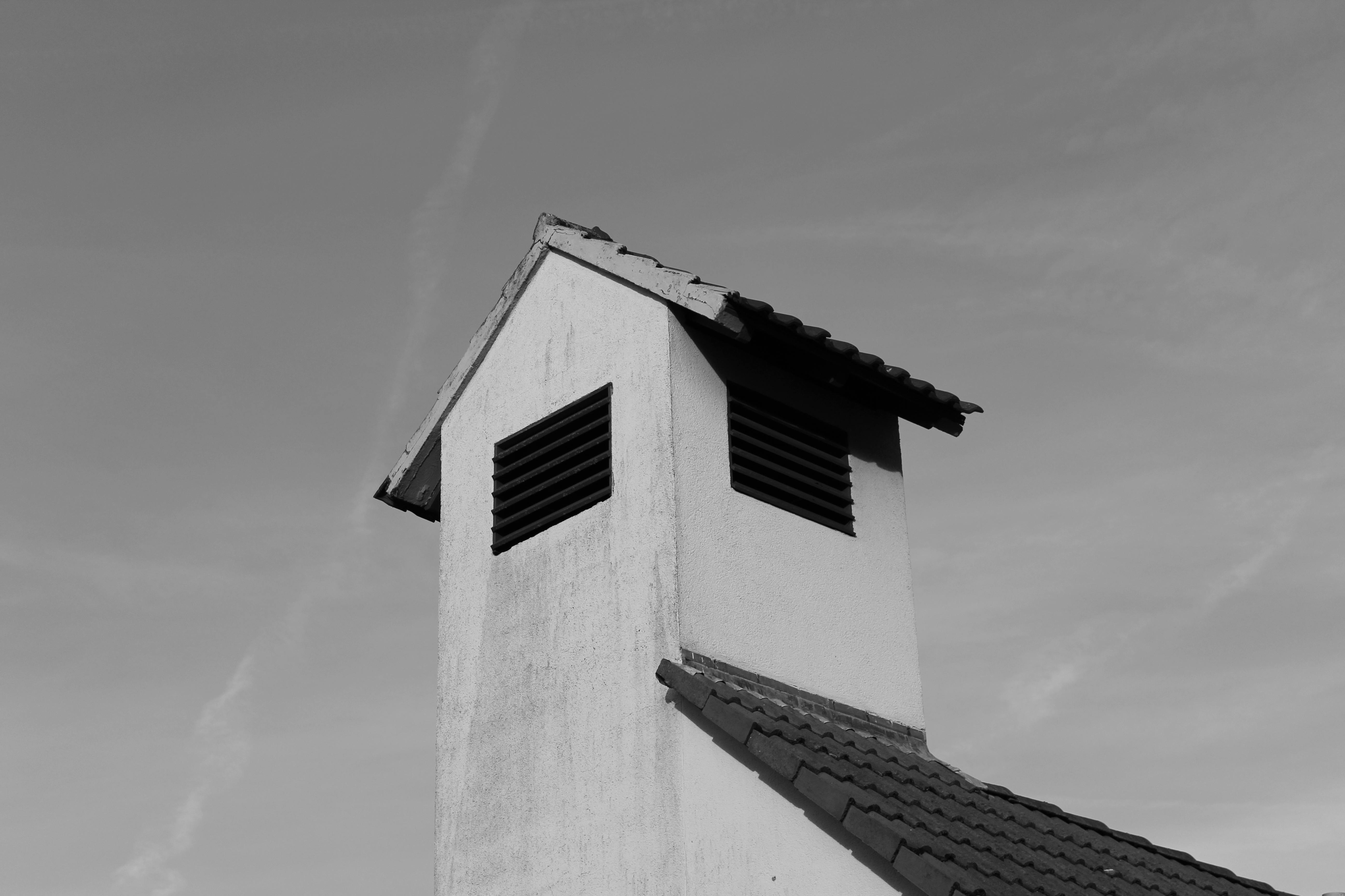 Zadarmo Monochromatický obraz strechy budovy zobrazujúci minimalistickú architektúru na pozadí jasnej oblohy. Fotka z fotobanky