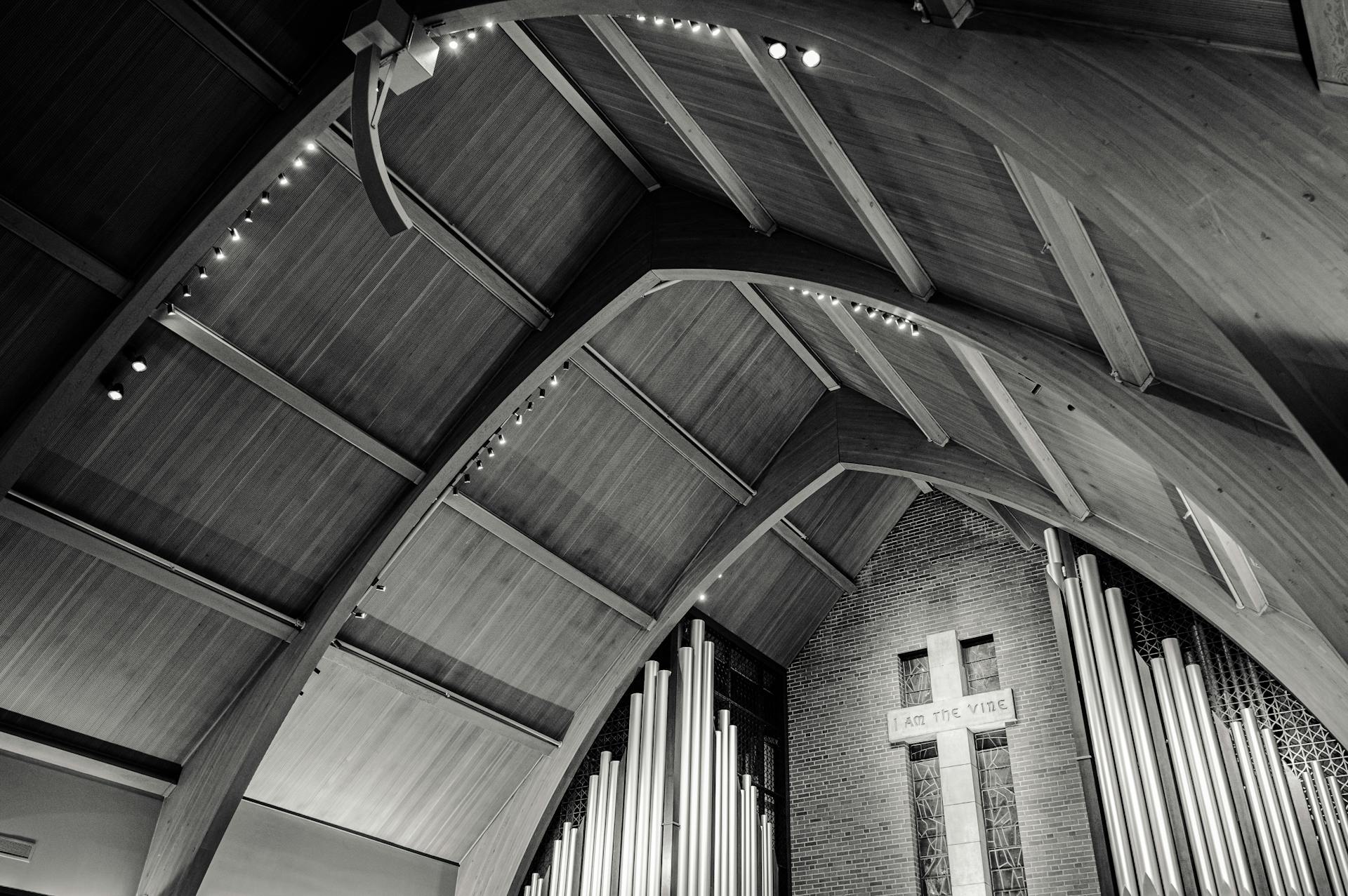 Striking interior of a modern church featuring wooden arches and organ pipes.