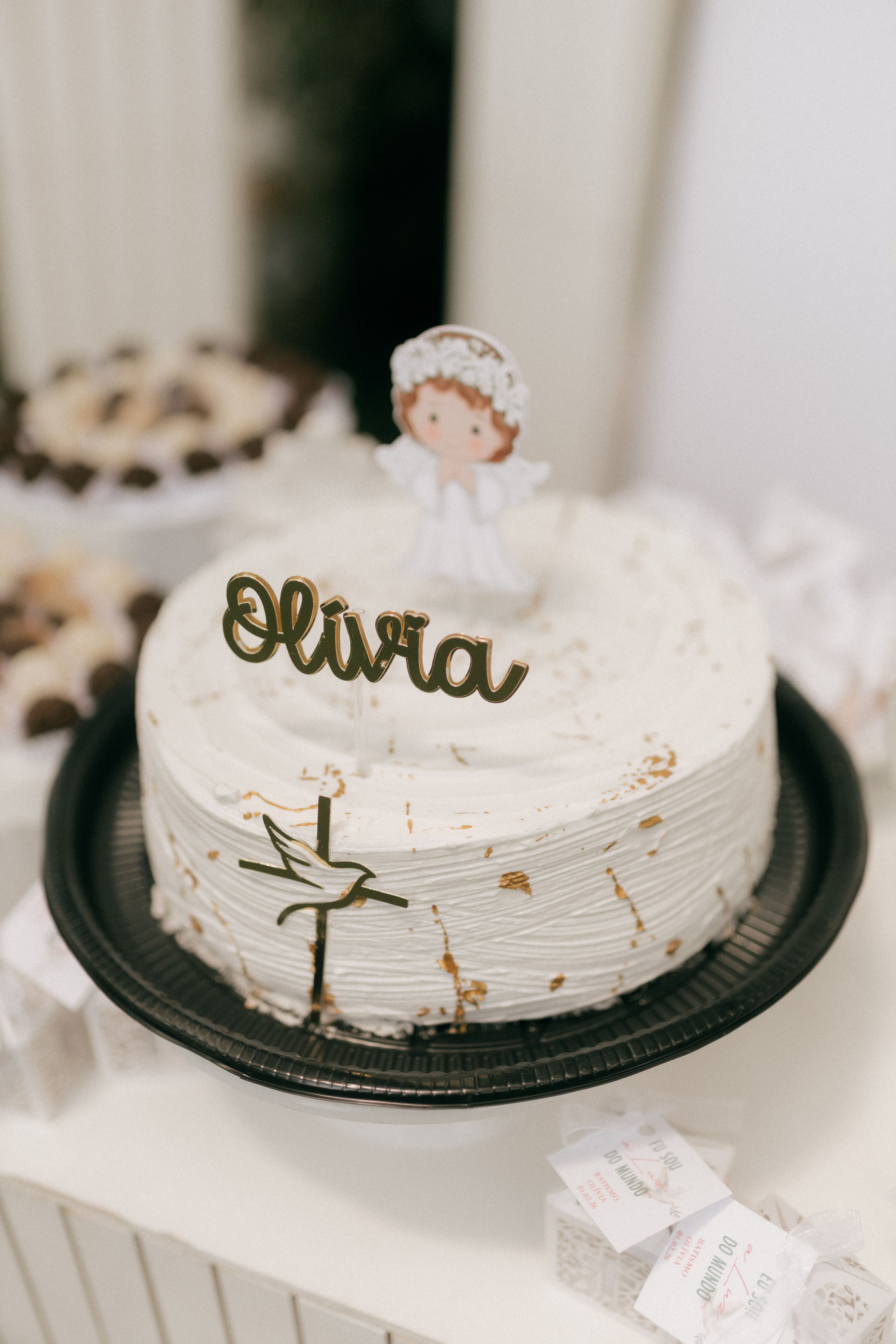 A beautifully decorated white cake featuring a Christening topper and the name 'Olivia' in elegant script.