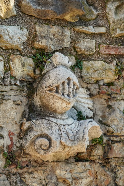 Free Detailed view of a Gothic stone sculpture embedded in an ancient stone wall outdoors. Stock Photo