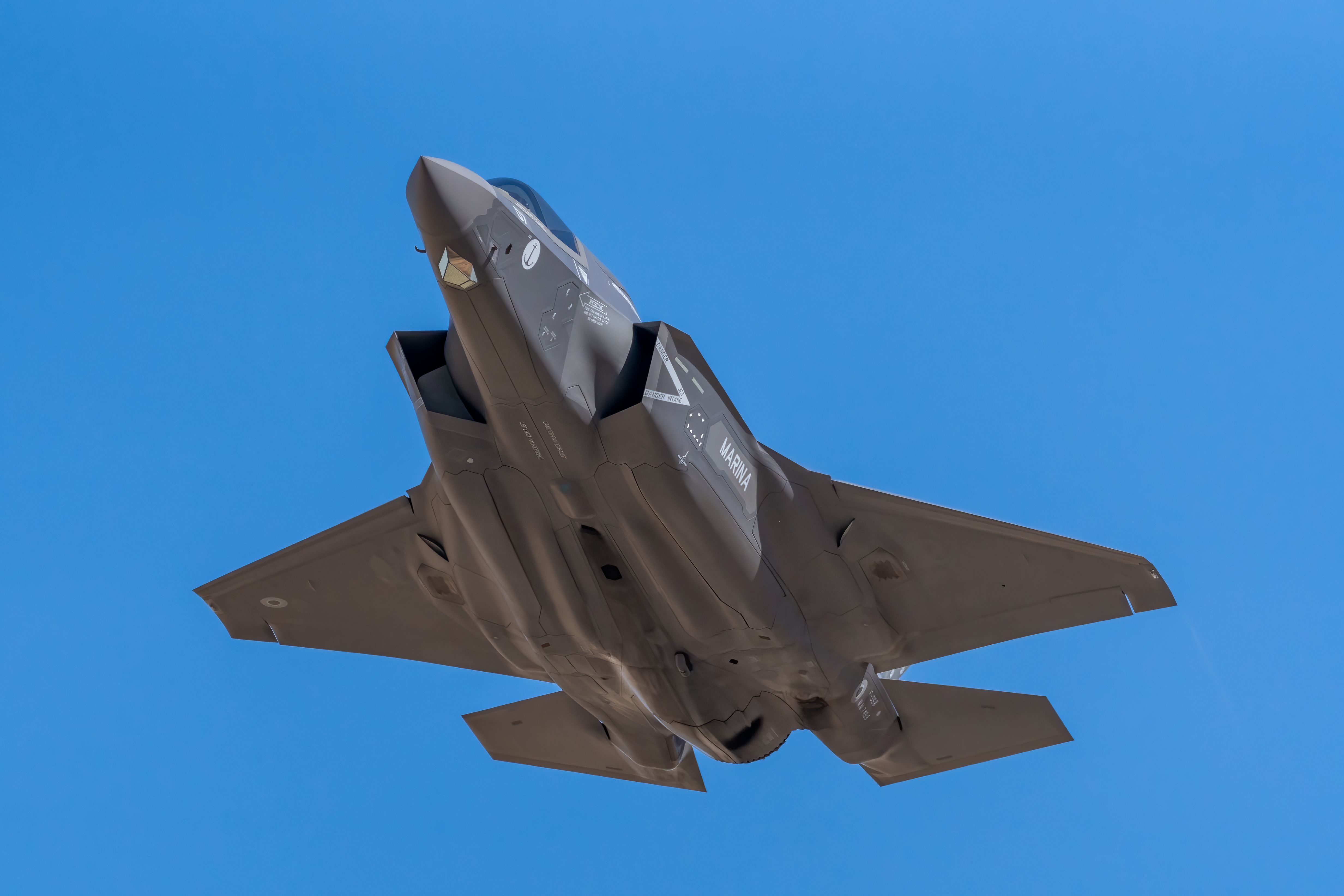 A stealth fighter jet flying through a clear blue sky.