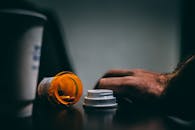 桌子上，一个打开的处方药瓶和一只情绪化的手点燃了场景，描绘了保健主题