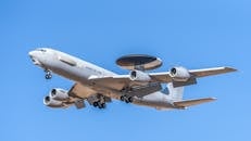 Military AWACS Aircraft in Flight Over Blue Sky