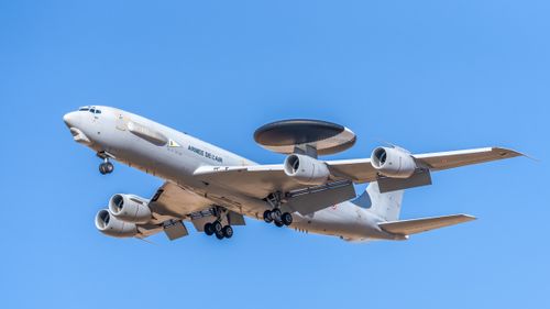 Free A military AWACS aircraft flying against a clear blue sky, showcasing aerial surveillance capabilities. Stock Photo