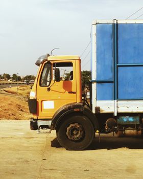 A colorful truck stands parked on a road in Nigeria, showcasing vibrant orange and blue colors.