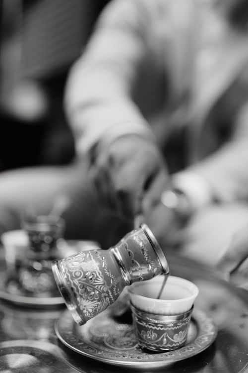 Free Close-up of a hand pouring Turkish coffee in an intricately designed cup. Stock Photo