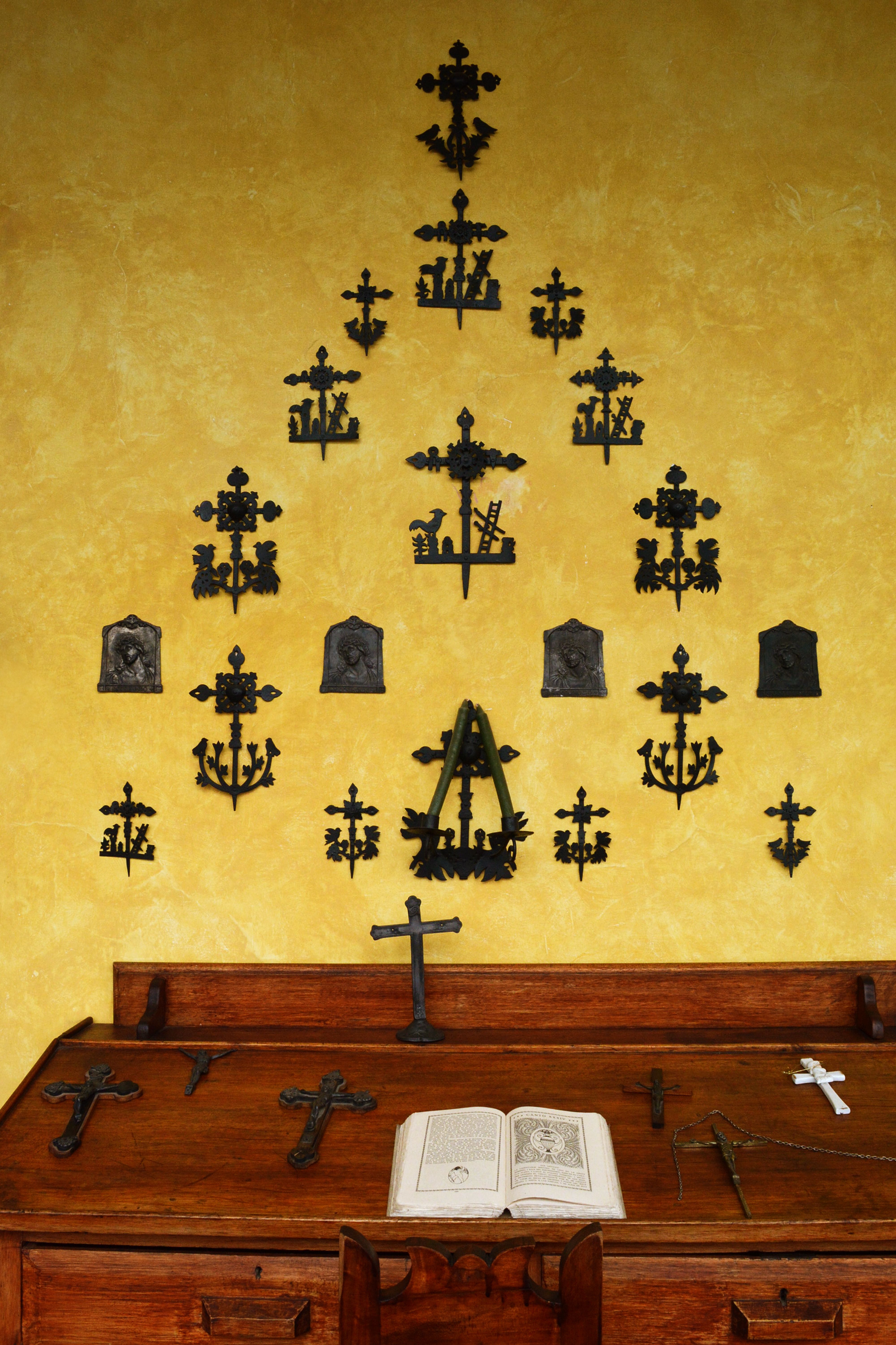 Artistic display of metal crosses and religious symbols on rustic wooden table.