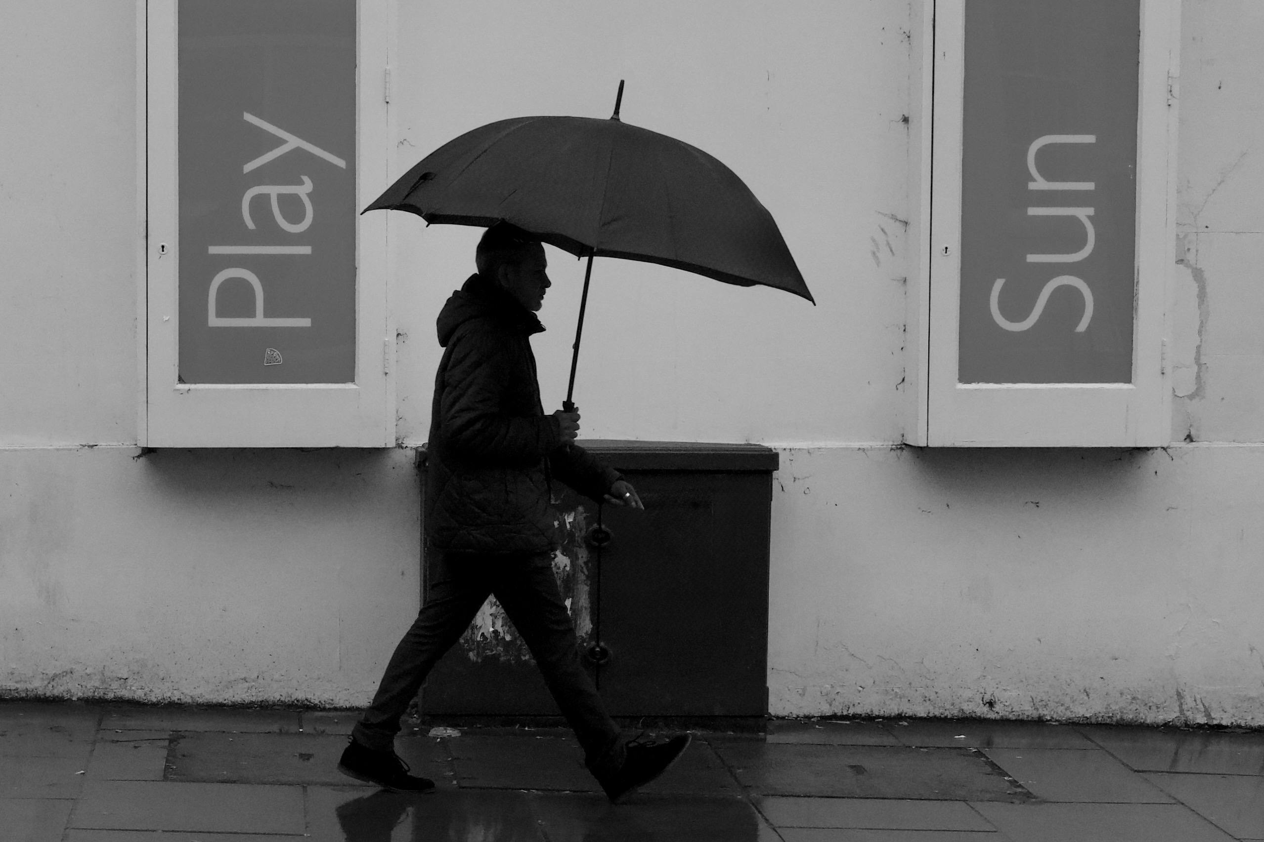 A person walks with a black umbrella on a rainy day in Cheltenham, England.