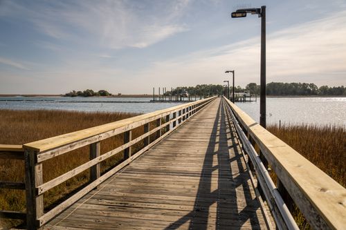 Free A calm scenic view of a wooden pier extending over a serene body of water, surrounded by nature. Stock Photo