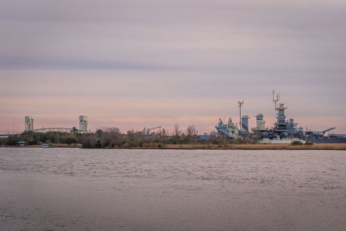 Free Scenic view of a battleship and river under a pastel sunset sky. Stock Photo