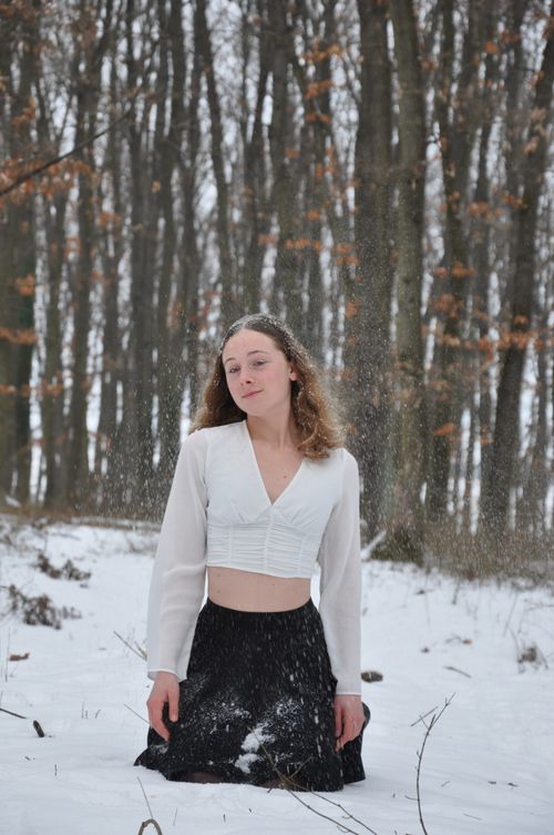 Free A young woman in a snowy forest, standing thoughtfully in winter attire. Stock Photo